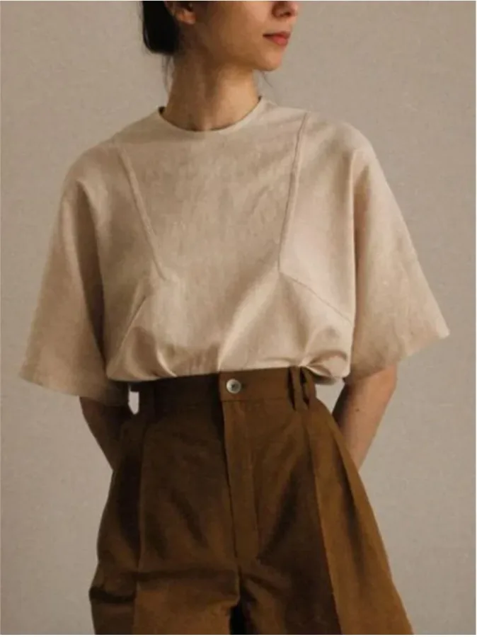 Minimal warm-neutral outfit pairing a relaxed beige short-sleeve top with high-waisted brown trousers.