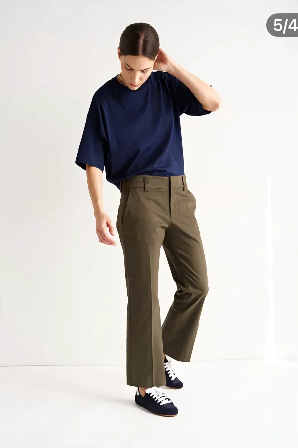 A minimalist smart-casual outfit pairing an oversized navy T-shirt with cropped olive trousers and clean navy sneakers.