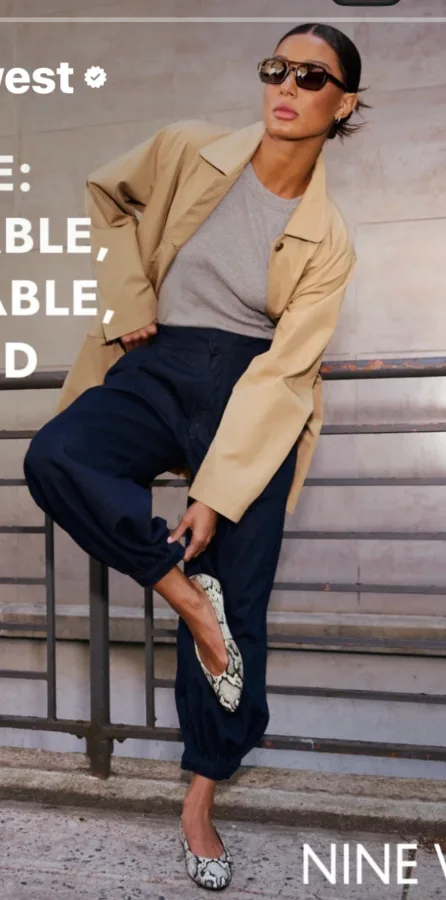 A polished smart-casual look pairing a relaxed beige trench coat and gray tee with dark navy trousers and snakeskin flats.